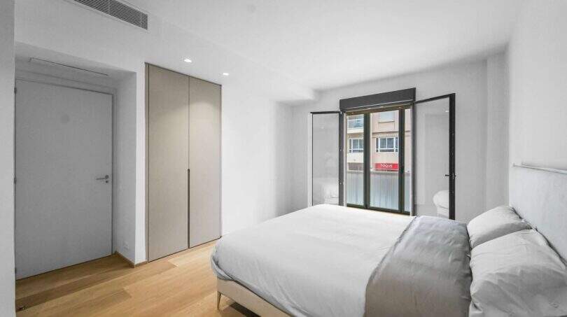 Helles Schlafzimmer der Luxuswohnung am Paseo Marítimo mit Doppelbett, Einbauschrank und Balkonzugang.