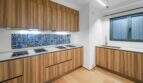 Moderne Küche der Luxuswohnung am Paseo Marítimo mit Holzfronten, weißer Arbeitsfläche und bunten Mosaikfliesen.