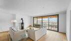 Helles Wohnzimmer der Luxuswohnung am Paseo Marítimo mit Kamin, Sofas und Balkon mit Hafenblick.