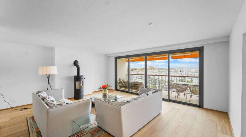 Helles Wohnzimmer der Luxuswohnung am Paseo Marítimo mit Kamin, Sofas und Balkon mit Hafenblick.