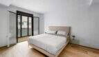 Helles Schlafzimmer der Luxuswohnung am Paseo Marítimo mit Doppelbett, Holzboden und Balkonzugang.