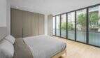 Helles Schlafzimmer der Luxuswohnung in Palma mit Parkettboden, Einbauschränken und großer Glasfront.
