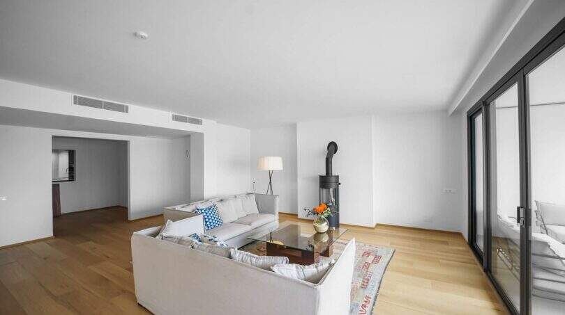 Helles Wohnzimmer der Luxuswohnung am Paseo Marítimo mit Holzboden, Kaminofen und Zugang zur Terrasse.
