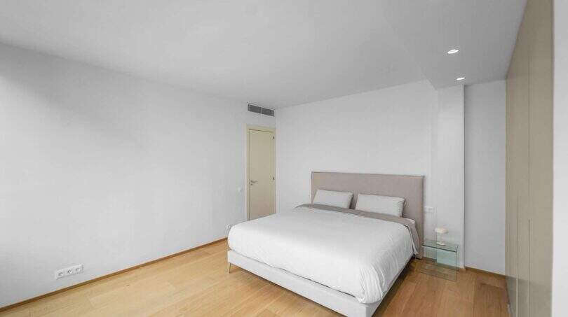 Helles Schlafzimmer der Luxuswohnung am Paseo Marítimo mit Doppelbett, Parkettboden und modernen Einbauspots.
