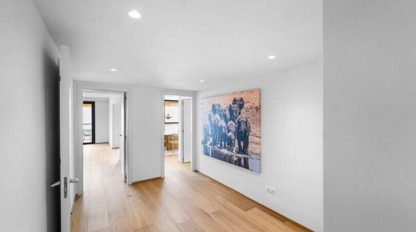 Heller Flur der Luxuswohnung am Paseo Marítimo mit Holzboden, Einbauspots und großem Elefanten-Kunstwerk.