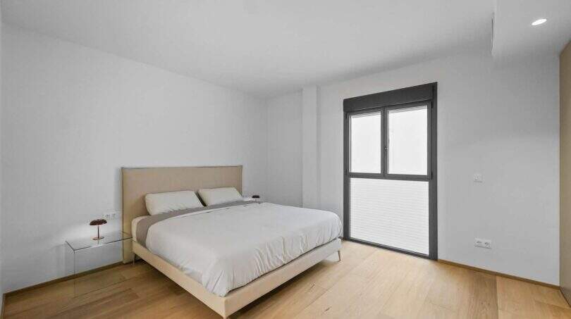 Helles Schlafzimmer der Luxuswohnung am Paseo Marítimo mit Parkettboden, Doppelbett und Balkonzugang.