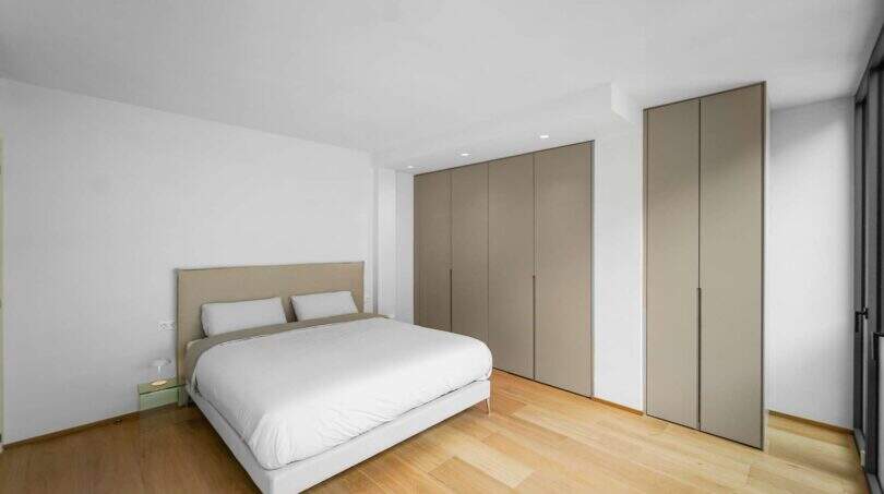 Helles Schlafzimmer der Luxuswohnung am Paseo Marítimo mit Doppelbett, Parkettboden und modernen Einbauschränken.