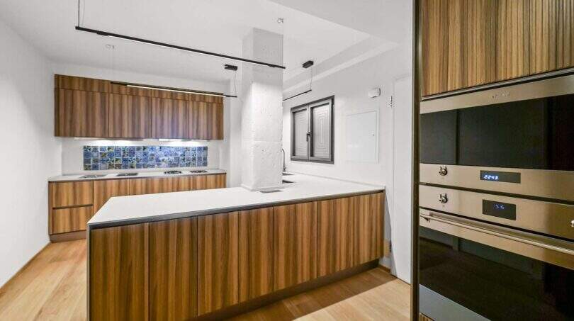 Moderne Küche der Luxuswohnung in Palma mit Holzfronten, Kücheninsel und hochwertigen Einbaugeräten.