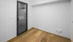 Leeres Zimmer der Luxuswohnung in Palma mit Holzboden, weißen Wänden und moderner Glastür.