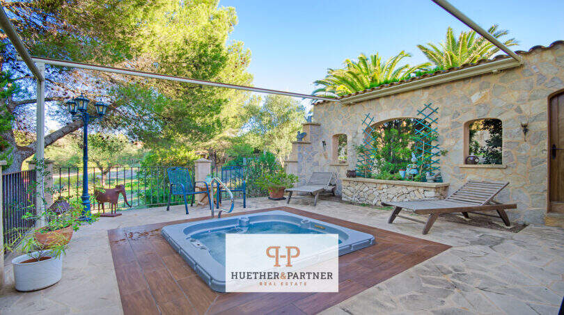 Finca Son Macià: Terrasse mit eingelassenem Jacuzzi, Natursteinmauer, Liegestühlen und üppigem Grün