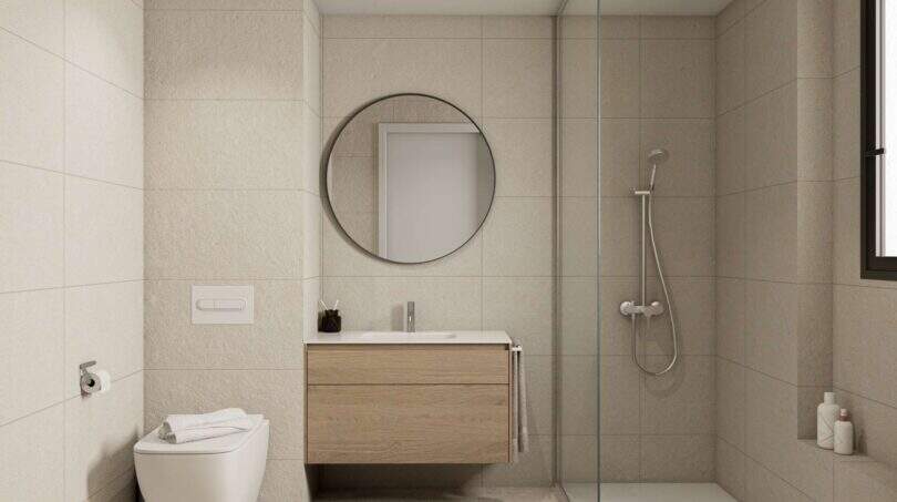 Modernes Badezimmer mit Walk-in-Dusche, Holzwaschtisch & Rundspiegel in Erdgeschoss-Wohnung Porto Cristo