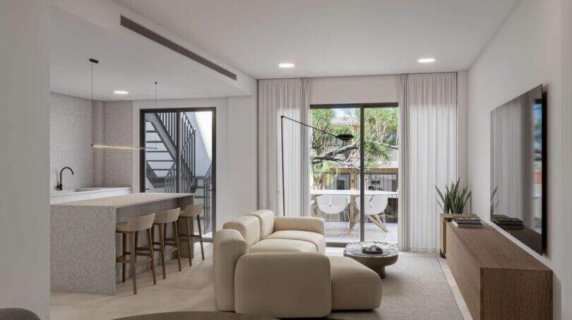 Bright living room with open kitchen, cream-colored sofa and balcony access in the new Porto Cristo building