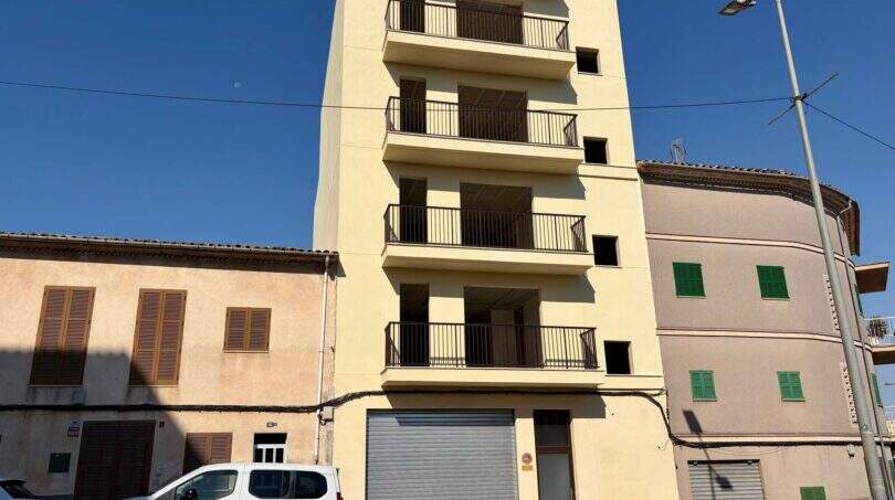 Mehrstöckiges Wohngebäude im Rohbau mit Balkonen in Manacor, flankiert von Nachbargebäuden, sonnige Außenansicht.