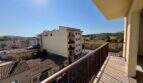 Balkon mit Holzgeländer und Blick auf Manacors Stadtbild, Felder und Hügel bei sonnigem Wetter
