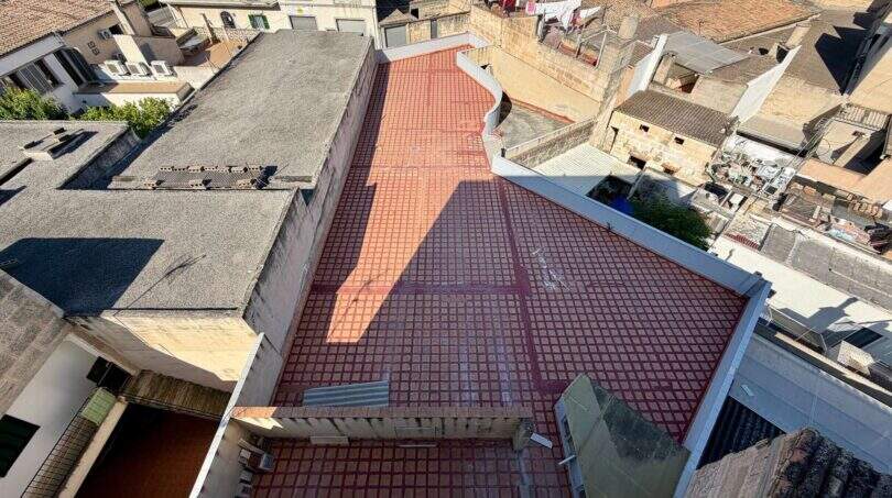 Luftaufnahme der Dachterrasse eines Rohbaus in Manacor mit roten Fliesen und umliegender Altstadtbebauung.