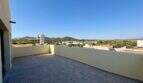 Weitläufige Dachterrasse mit Fliesenbelag, Blick auf Manacor, Wasserturm und Hügellandschaft, klarer Himmel
