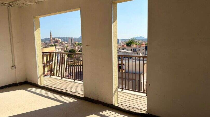 Leerer Rohbau-Raum mit zwei großen Fenstertüren, Balkon und Stadtblick auf Manacor mit Kirchturm