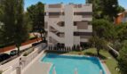 Modernes Apartmentgebäude in Canyamel mit gemeinschaftlichem Pool, Grünanlage und Außentreppe, nahe dem Meer.