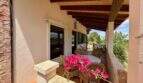 Überdachte Terrasse der Finca bei Sant Joan mit Rattanmöbeln, Holzbalkendecke und blühender Bougainvillea