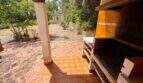 Überdachte Terrasse mit Grillstation und Terrakottafliesen, Blick auf den naturnahen Garten der Finca bei Vilafranca
