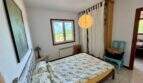 Helles Schlafzimmer der Finca bei Vilafranca mit Doppelbett, Pendelleuchte und Fenster mit Grünblick.