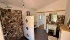 Badezimmer der Finca mit Natursteinwand, bodenebener Dusche, Waschbecken und WC
