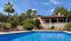 Finca Sant Joan: Blauer Pool mit Leiter, Terrassenhaus, Palme und üppigem Grün unter Sonnenhimmel