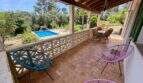 Überdachte Terrasse der Finca mit bunten Acapulco-Stühlen, Blick auf Pool und grüne Natur in Sant Joan