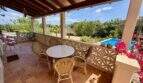 Überdachte Terrasse mit Rattanmöbeln, Blick auf Pool und mediterrane Landschaft der Finca bei Vilafranca