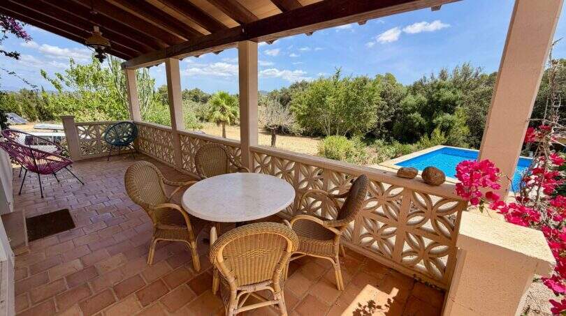 Überdachte Terrasse mit Rattanmöbeln, Blick auf Pool und mediterrane Landschaft der Finca bei Vilafranca