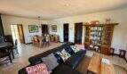 Geräumiges Wohnzimmer der Finca mit schwarzem Ledersofa, Holzcouchtisch, Bücherregal und offenem Essbereich