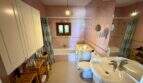 Geräumiges Badezimmer der Finca bei Vilafranca de Bonany mit Badewanne, Dusche, Waschbecken und rosa Wandfliesen.
