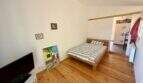 Schlafzimmer der Finca mit Holzboden, Doppelbett, TV und Durchgang zum Bad