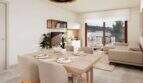Helles Wohn-Esszimmer mit Holztisch, Sofabereich und Zugang zur Dachterrasse im Duplex-Penthouse Canyamel