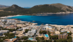 Luftaufnahme von Cala Ratjada mit türkisblauem Meer, Sandstrand und Hotelanlage, umgeben von grünen Hügeln.