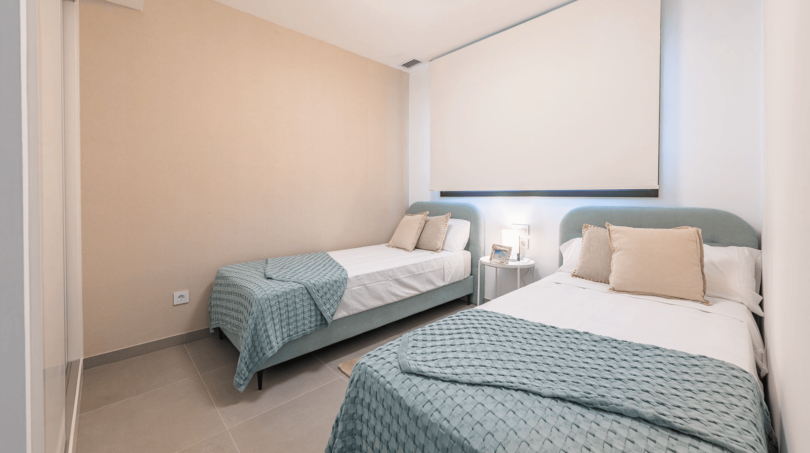 Helles Schlafzimmer mit zwei Einzelbetten, mintgrünen Tagesdecken und modernem Design in Cala Ratjada