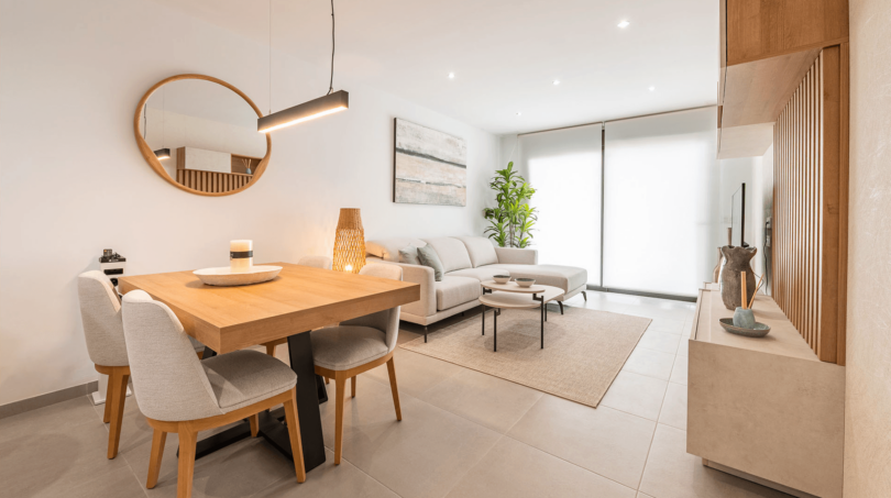 Helles Wohn- und Esszimmer mit Holzmöbeln, grauem Sofa und großer Terrassentür in moderner Wohnung Cala Ratjada