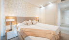 Helles Schlafzimmer der EG-Wohnung in Cala Ratjada mit Doppelbett, Einbauschrank und eleganter Mustertapete.
