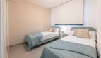 Helles Schlafzimmer mit zwei Einzelbetten, mintfarbenen Tagesdecken und modernem Design in EG-Wohnung Cala Ratjada