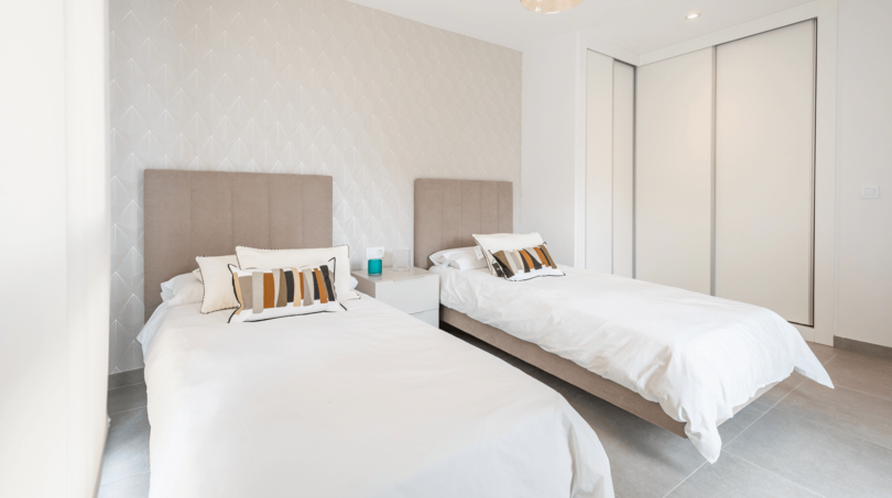 Helles Schlafzimmer mit zwei Einzelbetten, beigen Polsterkopfteilen und modernem Einbauschrank in DHH Cala Ratjada