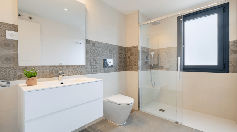 Modernes Badezimmer der DHH in Cala Ratjada mit Glasdusche, schwebendem Waschtisch und Dekorfliesenband.