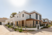 Modern semi-detached house in Cala Ratjada with natural stone cladding, glass balcony and well-maintained front garden.