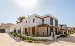 Moderne Doppelhaushälfte in Cala Ratjada mit Natursteinverkleidung, Glasbalkon und gepflegtem Vorgarten.