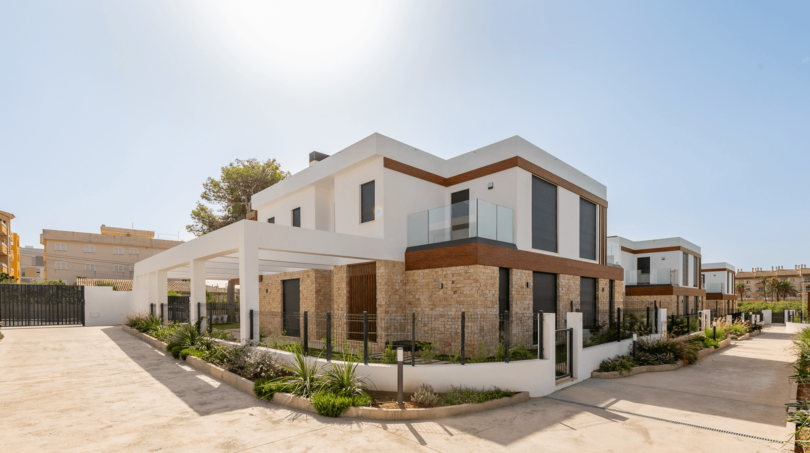 Moderne Doppelhaushälfte in Cala Ratjada mit Natursteinverkleidung, Glasbalkon und gepflegtem Vorgarten.