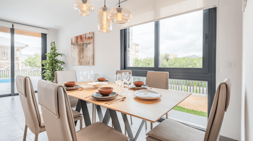 Modern Dining Room of the Semi-Detached House in Cala Ratjada with Wooden Table, Pendant Lights and Garden View