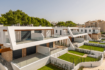 Modern semi-detached houses in Cala Ratjada with glass railings, wood accents and well-maintained green spaces.