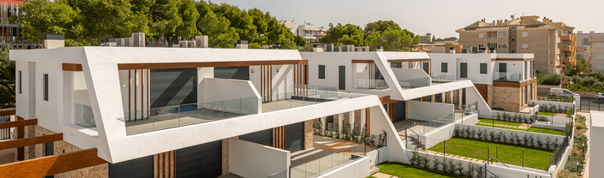 Modern semi-detached houses in Cala Ratjada with glass railings, wood accents and well-maintained green spaces.
