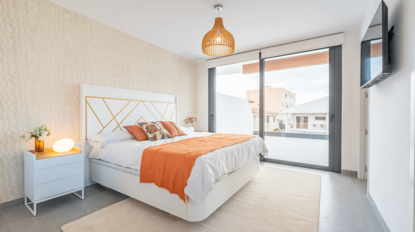 Helles Schlafzimmer der DHH in Cala Ratjada mit Doppelbett, orangenen Akzenten und Balkonzugang