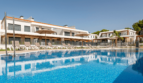 Großer Gemeinschaftspool mit Liegestühlen und moderner Wohnanlage in Cala Ratjada, Mallorca.