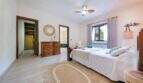 Luminoso dormitorio de la Finca Portocolom con cama doble, cómoda de madera, ventilador de techo y vestidor